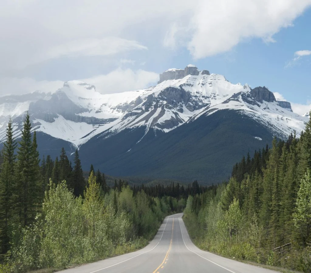 Panoramic view of a winding road surrounded by Canadian mountains and lakes