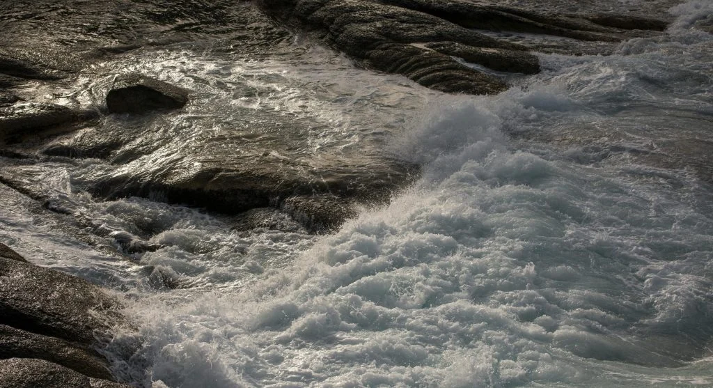 Rugged stone shoreline in Canada with turbulent water and visible texture
