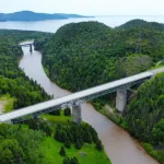 Panoramic view of a bridge crossing in Canada surrounded by lush greenery and mountains