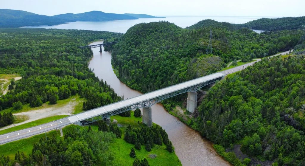 Panoramic view of a bridge crossing in Canada surrounded by lush greenery and mountains