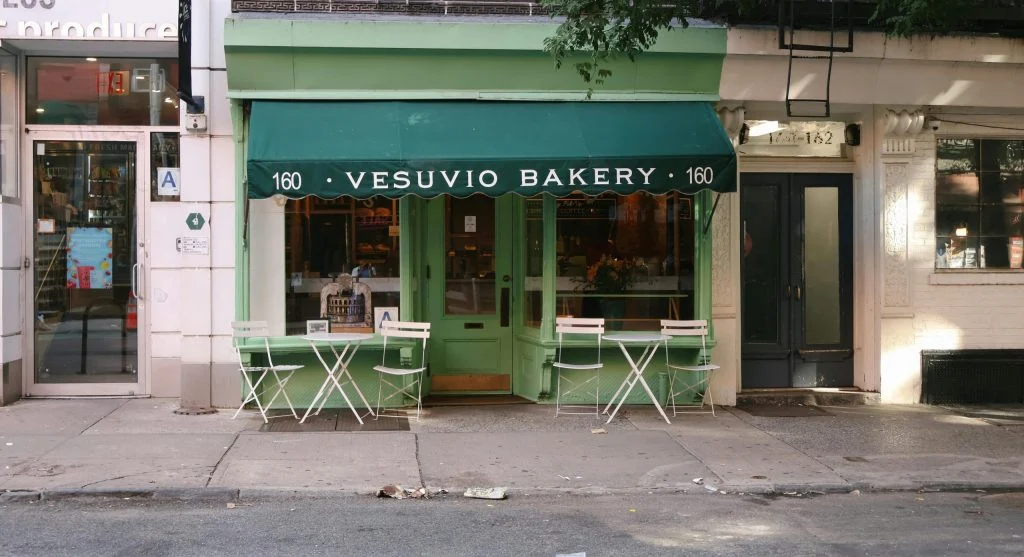 Warmly lit bakery with people gathered at tables, laughing and chatting