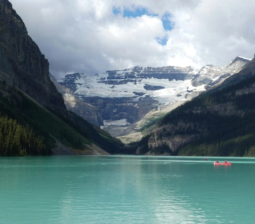 Person walking on a calm scenic path surrounded by trees and a lake in Canada